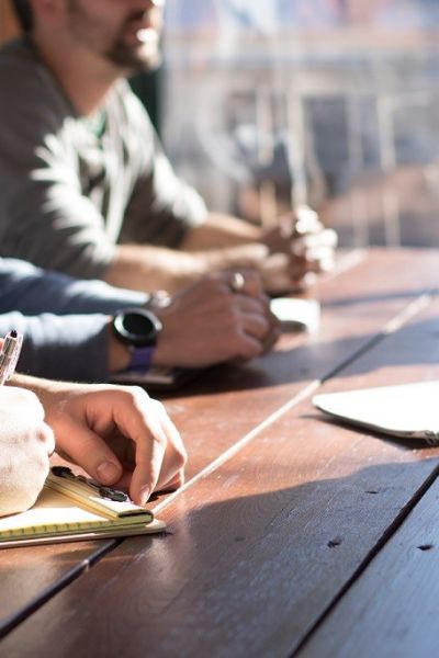 Closeup of people writing on paper on a table.