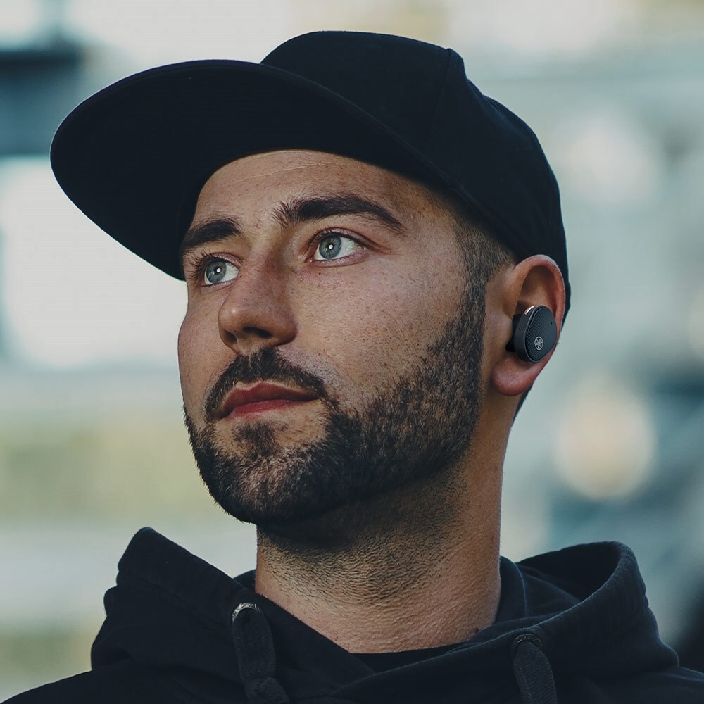 TW-E5B Guy with ball cap and hoodie wearing an earbud in his left ear.