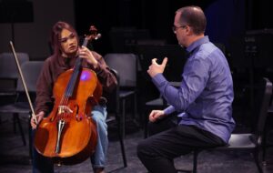 music educator sitting and talking with a cello student